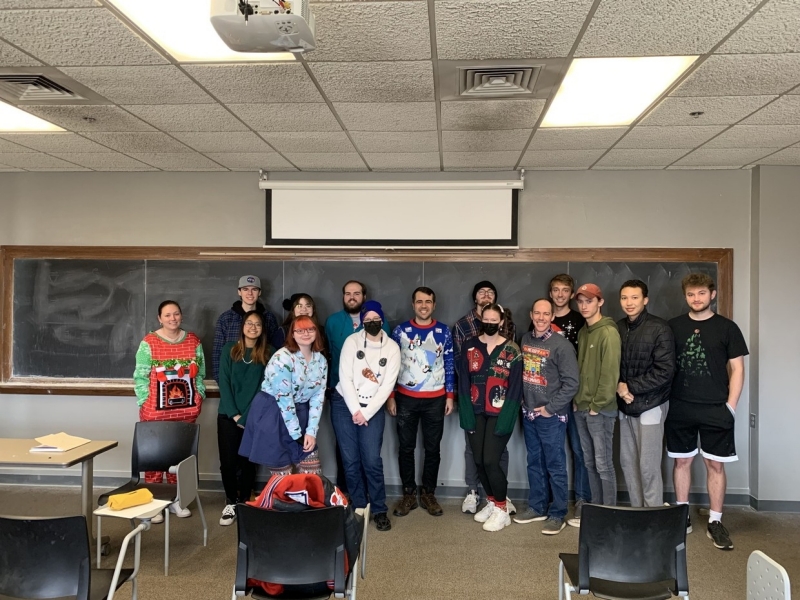 ASTR 4303 class posing for a picture, some of them wearing holiday sweaters.
