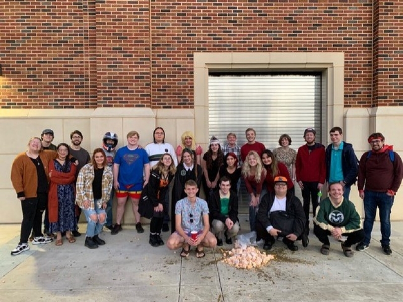 SPS posing for a picture behind a smashed pumpkin.