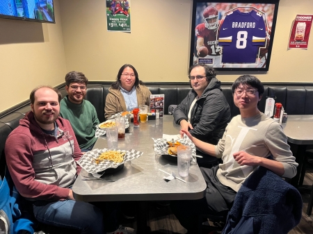 A small group from the High Energy Physics research group enjoying a meal at a restaurant.