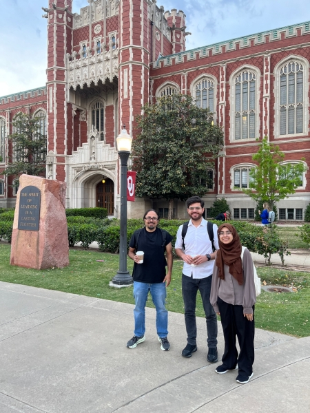 A small group from the High Energy Physics research group pose for a picture in front of the OU library.