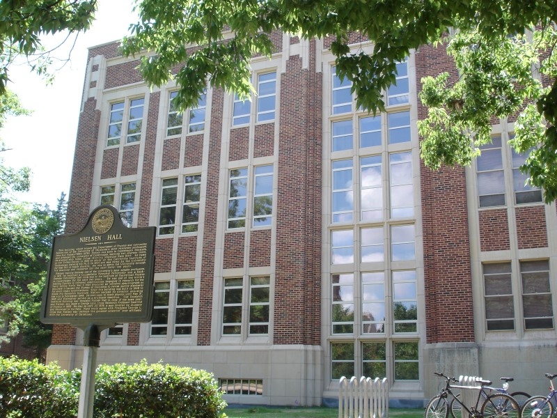 Image from outside Nielsen Hall with a plaque in front detailing information about the building.