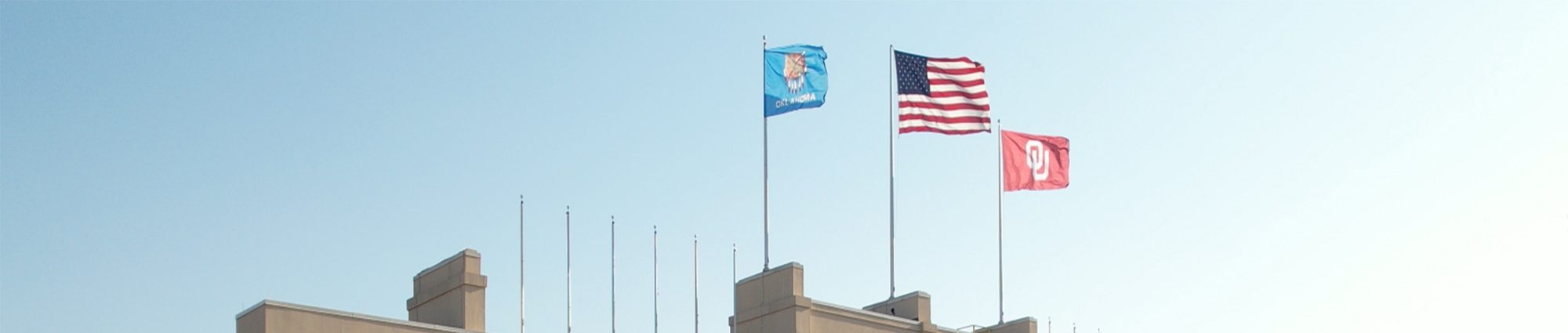 State of Oklahoma flag, US flag, and OU flag on top of building.