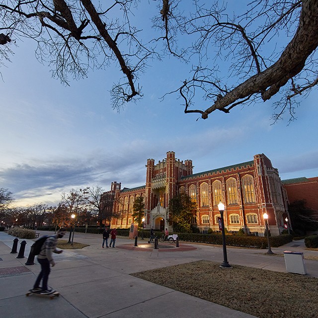People in front of the Bizzell Memorial Library at dusk.