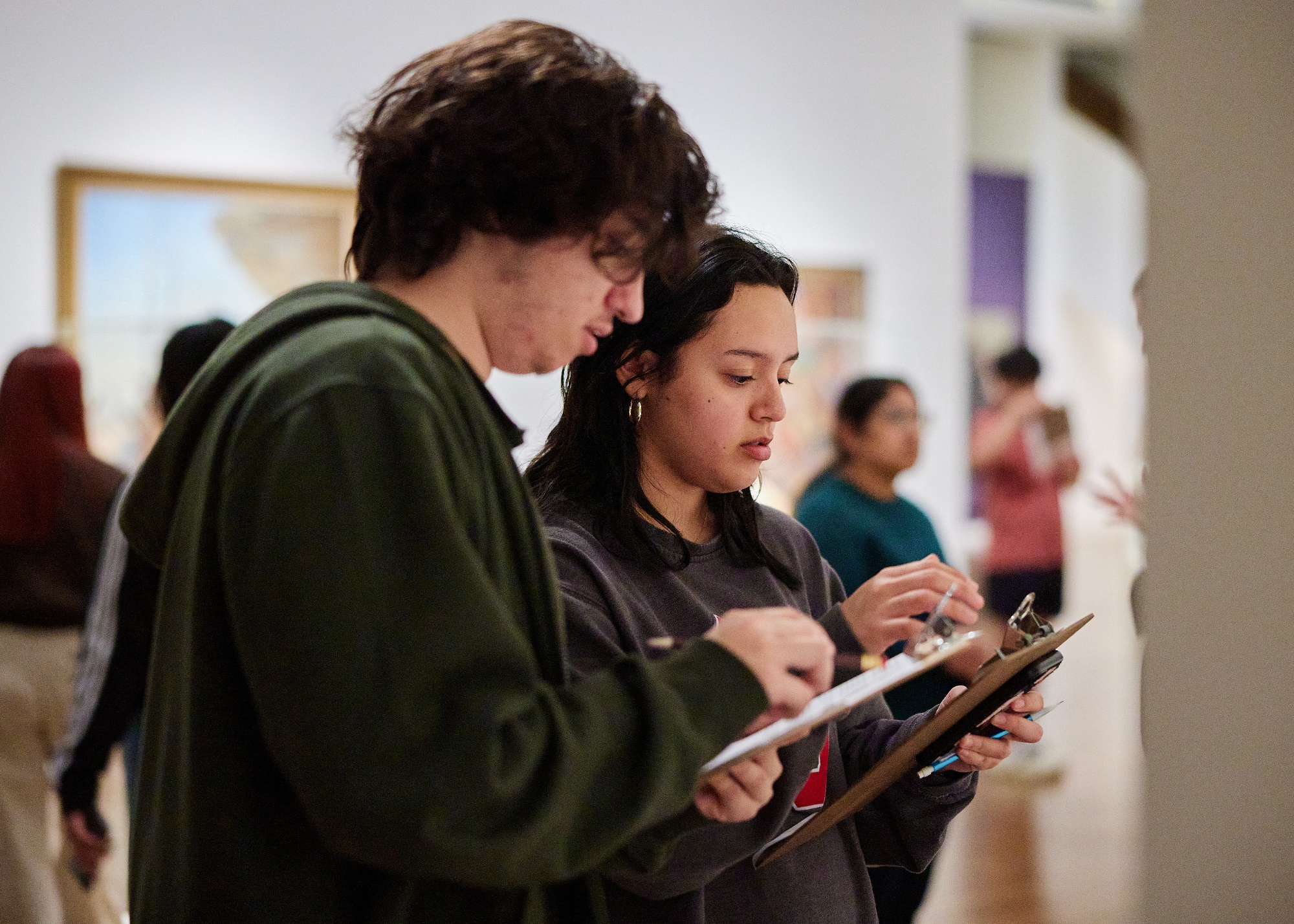 Two religious studies students take notes during class.