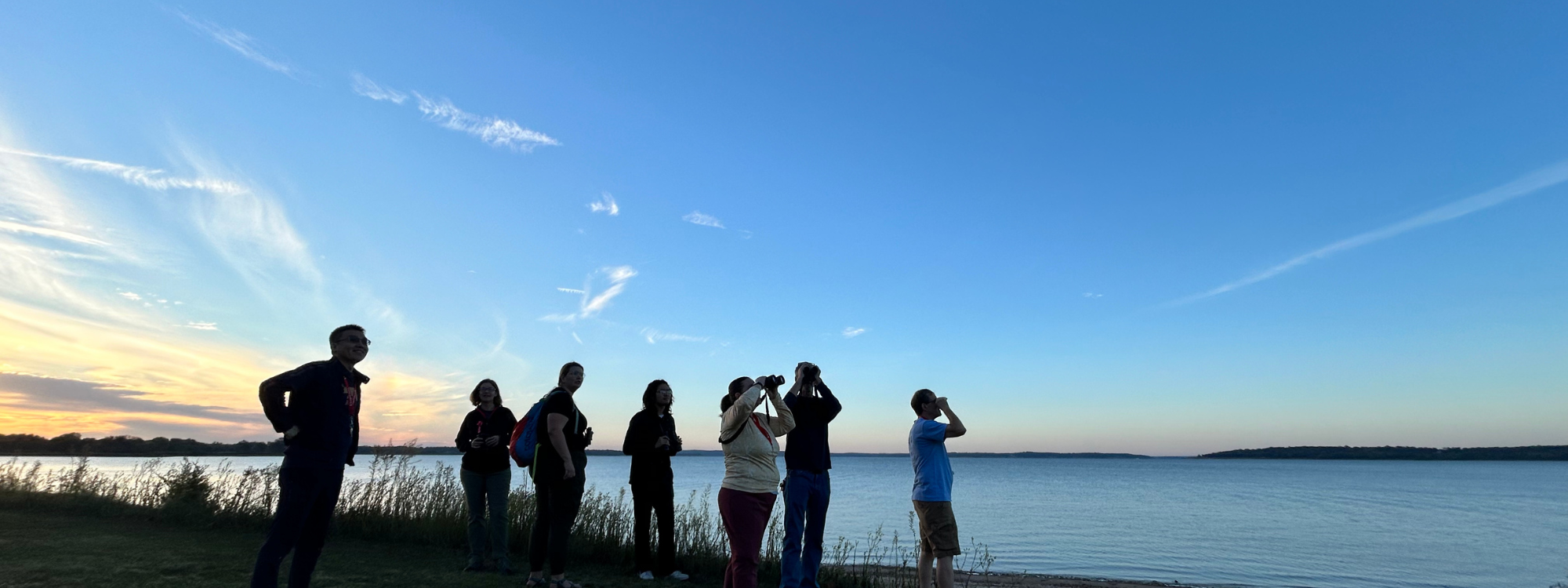 individuals standing on the shore of Lake Texoma looking at the sky.