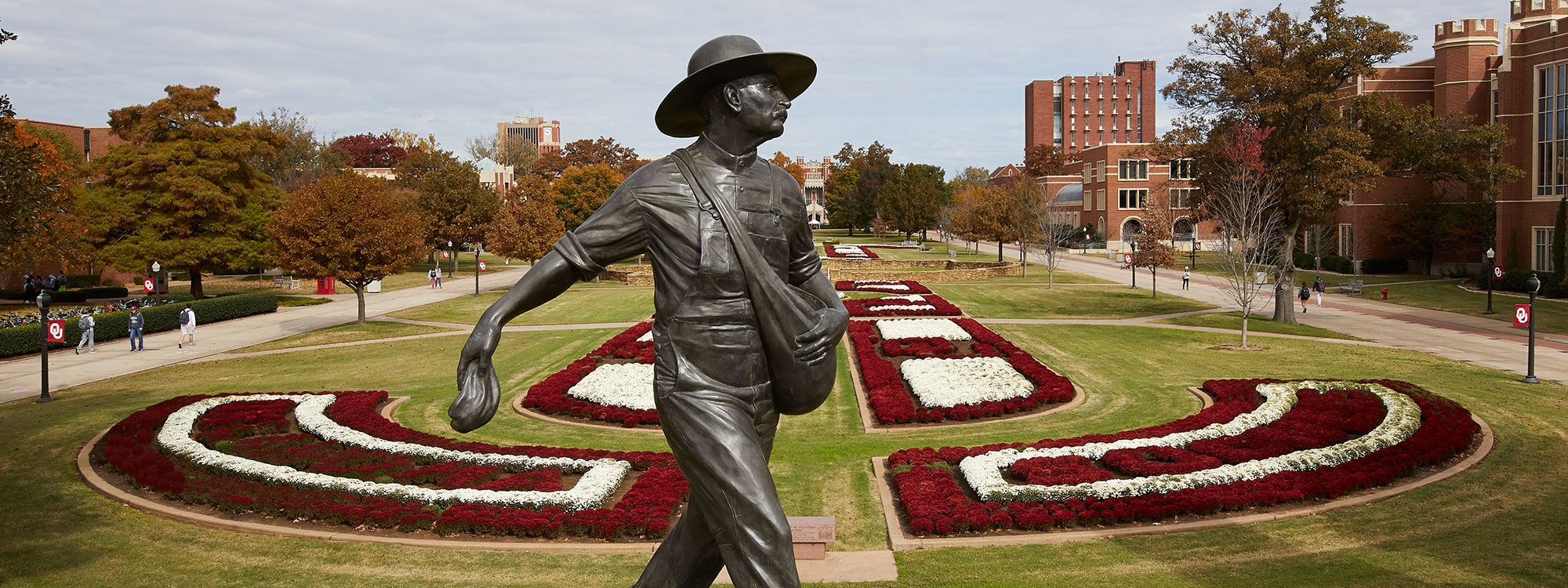 The seed sower statue framed by the grassy oval planted with crimson and white mums in geometric patterns.