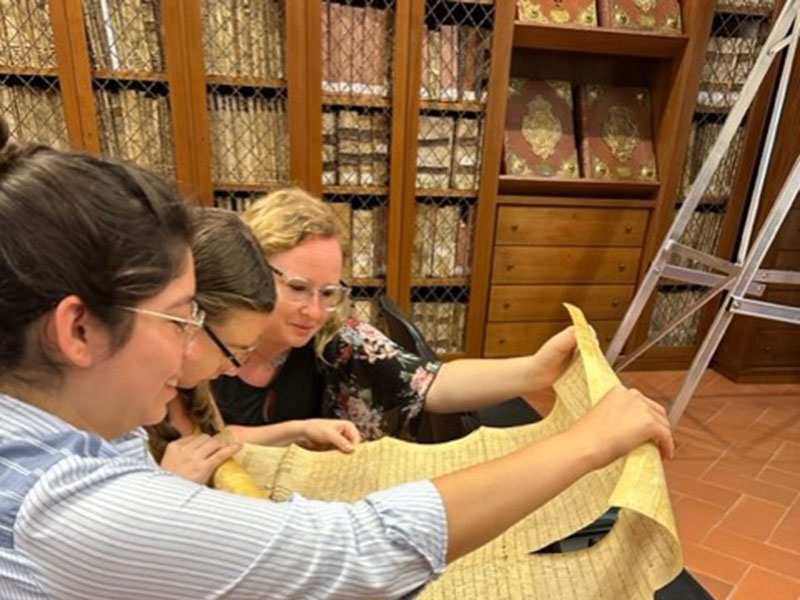 Students study parchment document in Italy.