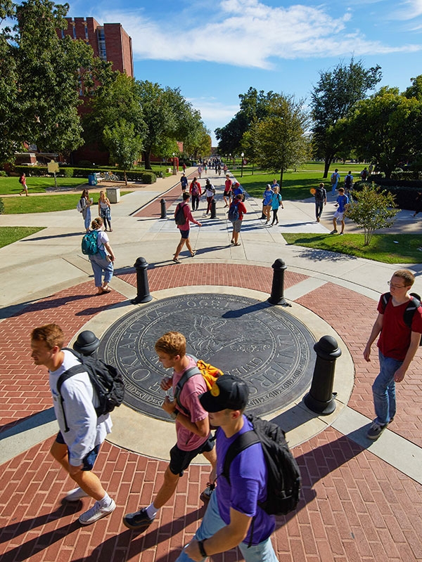 Students crossing the OU campus oval on a sunny day.