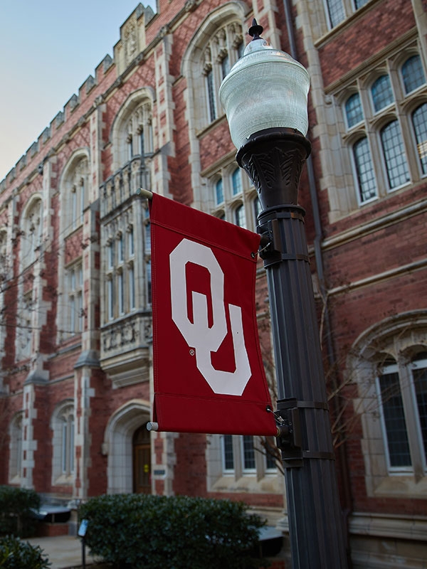 A view of a lamppost with OU banner in front of Evans Hall.