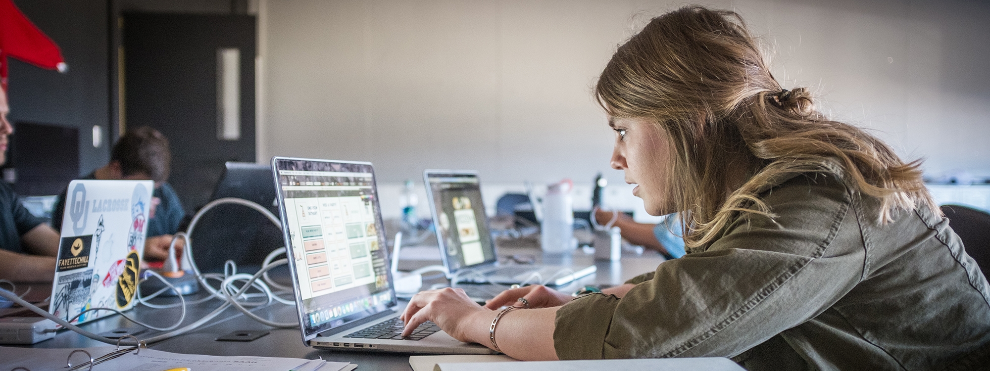 Students sitting at a table, working on laptops.