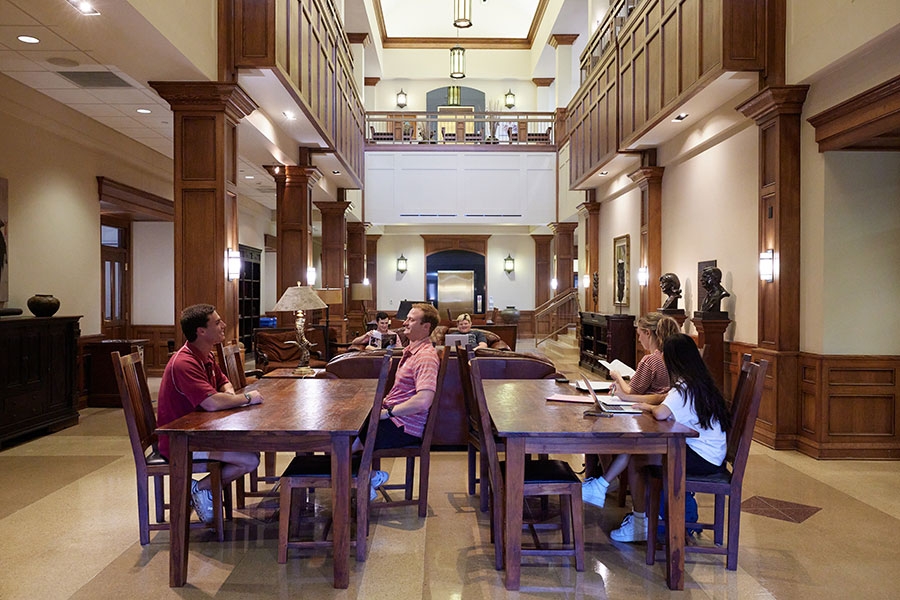 Students in atrium sitting at desks studying.