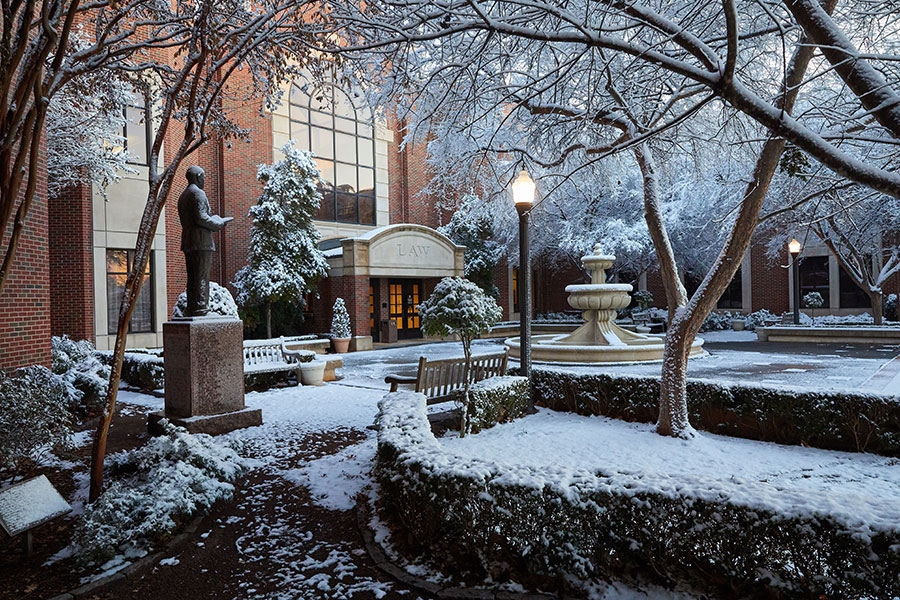 The courtyard of the Law School with statues, trees, and lampposts in winter.