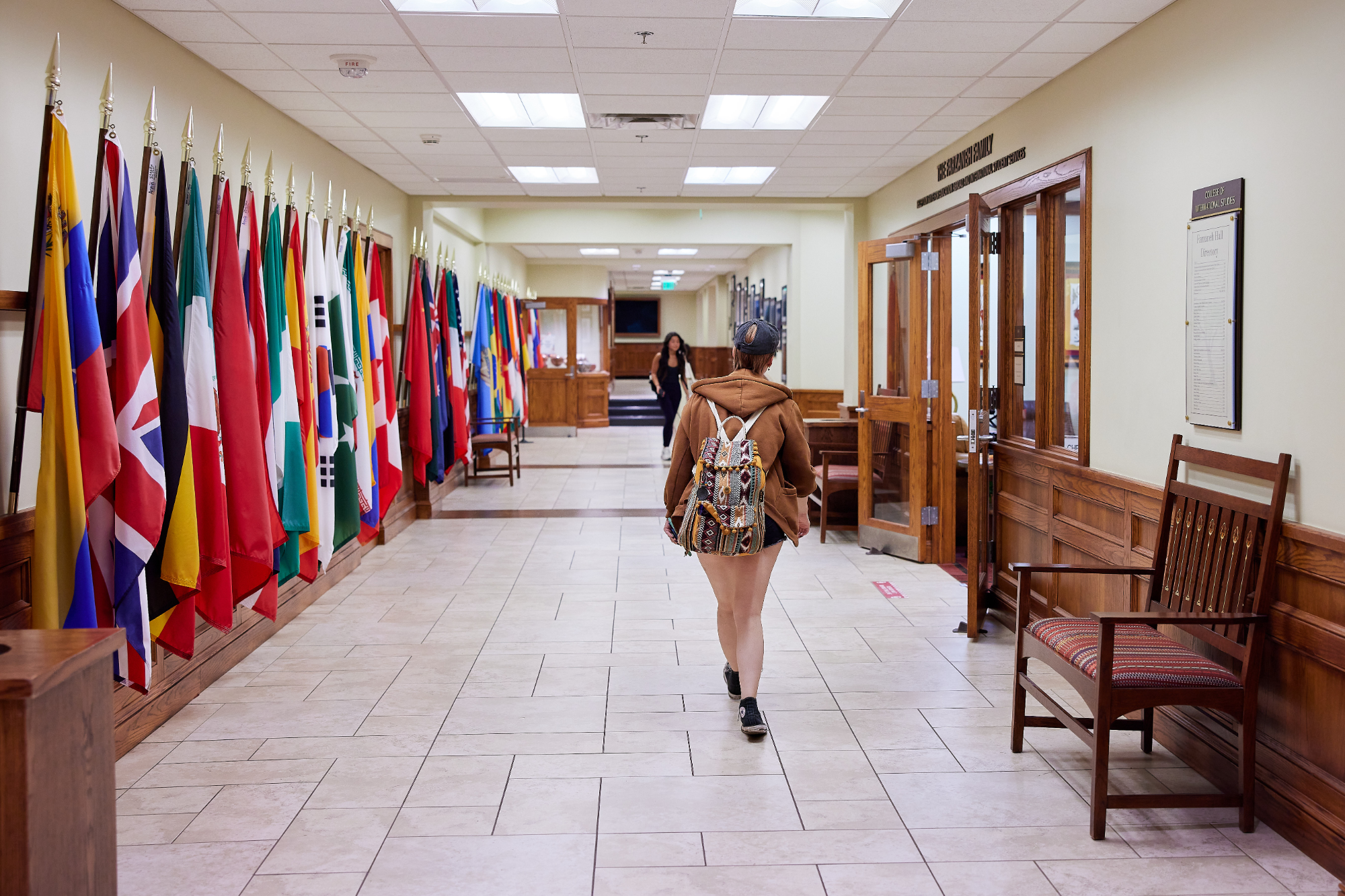 A student walking down a hallway lined with flags from many different countries.