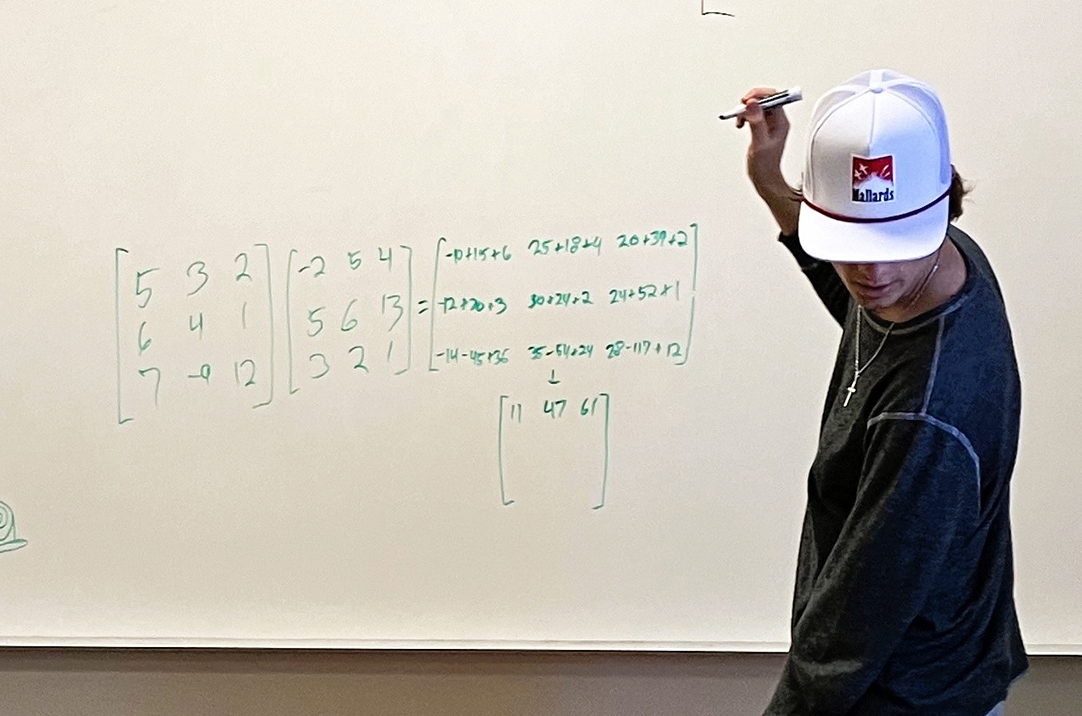 A student working on a math problem on a whiteboard.