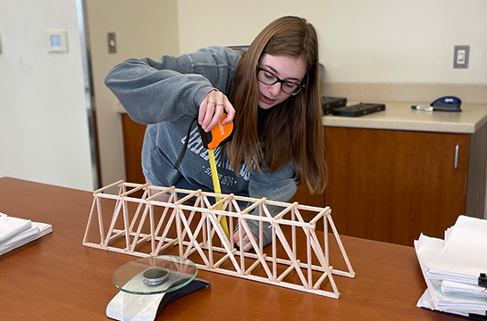 Student measuring their bridge as part of the model bridge competition