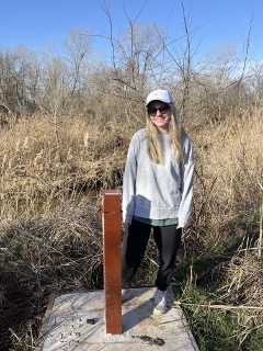 Sydney Nordquist standing next to landfill leachate collection well.
