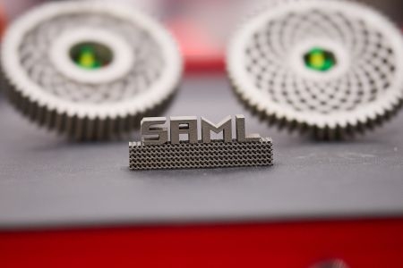 SAML logo metal figure with two round metal components sitting on a table. 