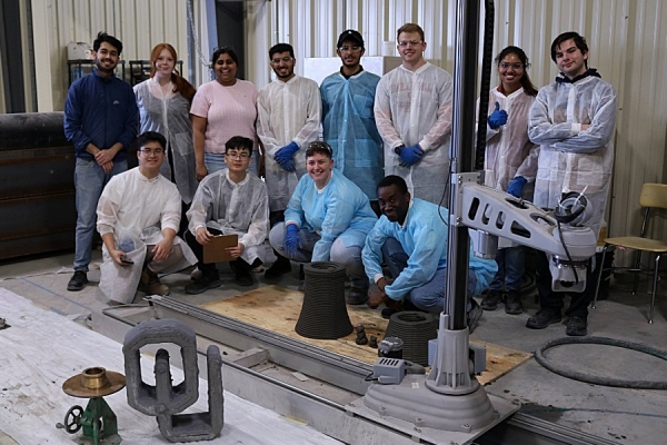 Students of the 3D concrete printing workshop gather around an O U concrete statue. 