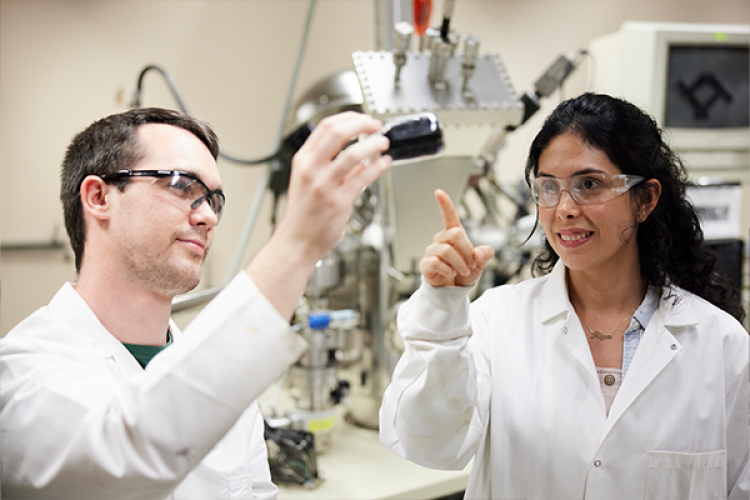 Two researchers looking at vial of liquid