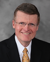 A man in a suit smiles for the camera.