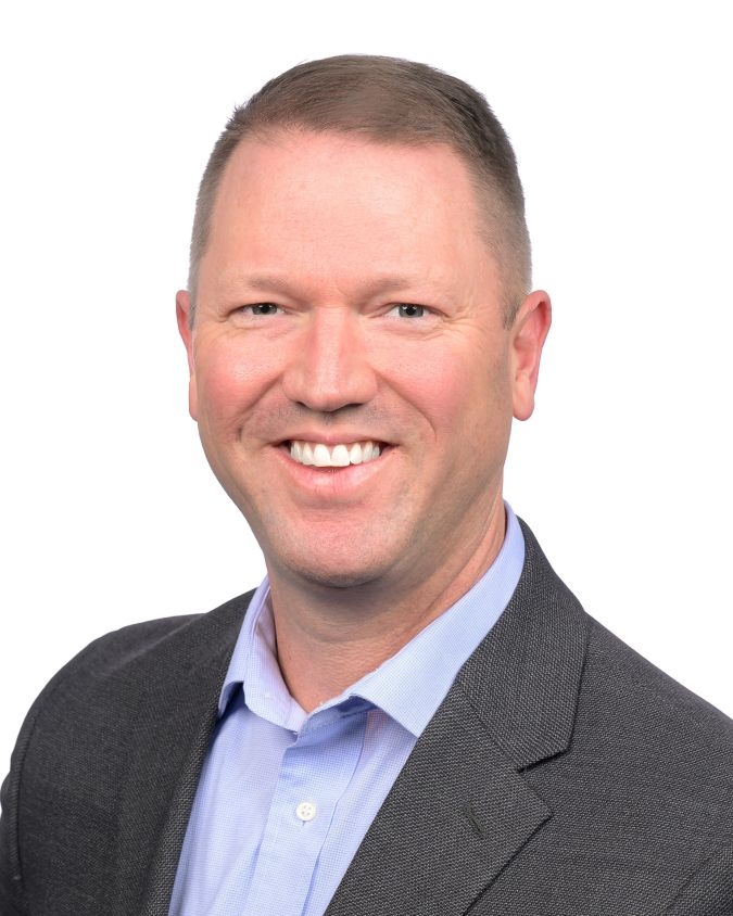 A man in a black suit smiling for the camera