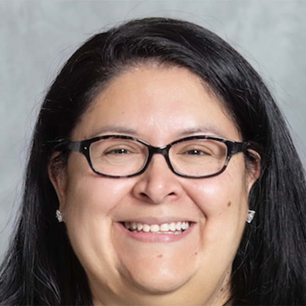 Woman with dark hair wearing a black blouse and glasses