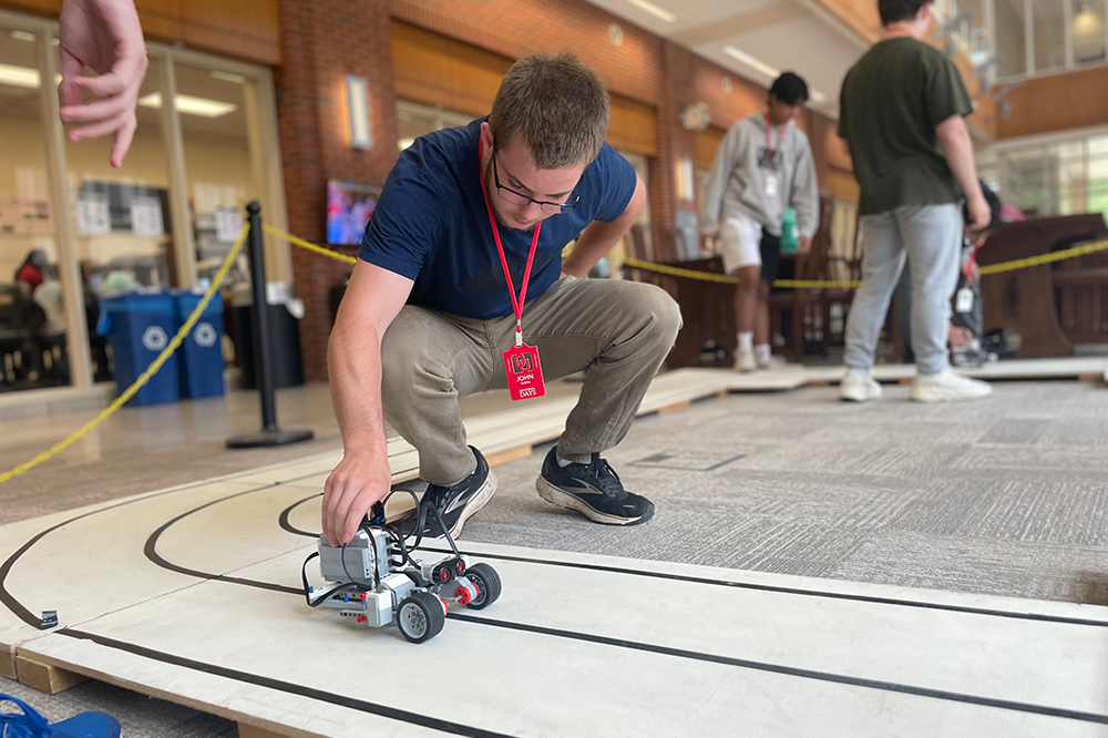High school student handles small, robotic fuel cell car on a track