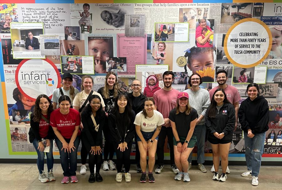 Group of OU-Tulsa students standing in front of a wall at Emergency Infant Services.
