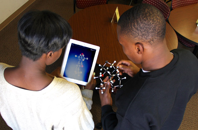 Two students looking at an iPAD and a fidget toy. 