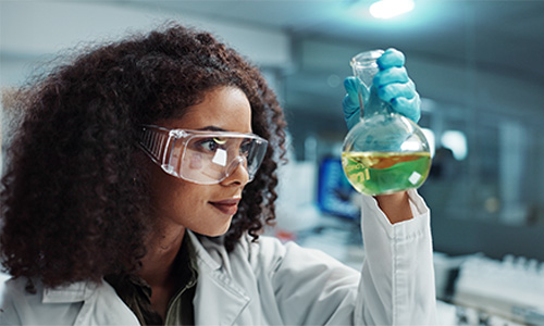 Chemistry student in lab looking at experiment in a beaker