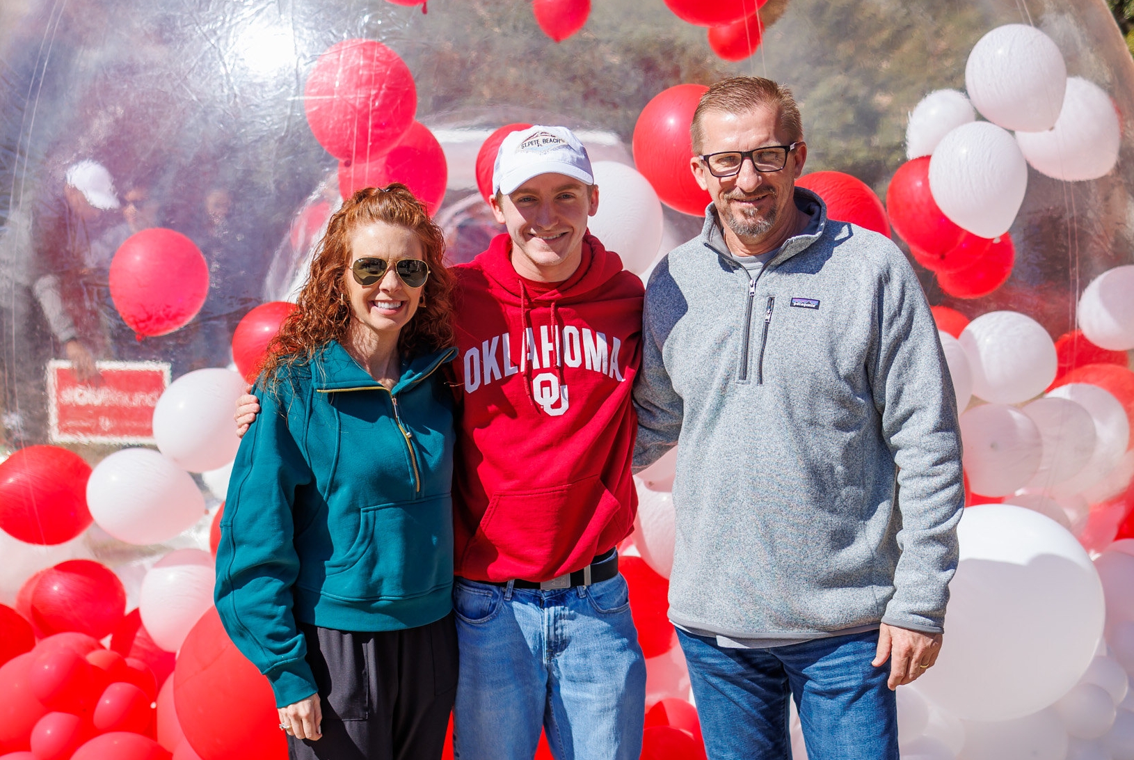 A mother, father, and student smiling together on campus.