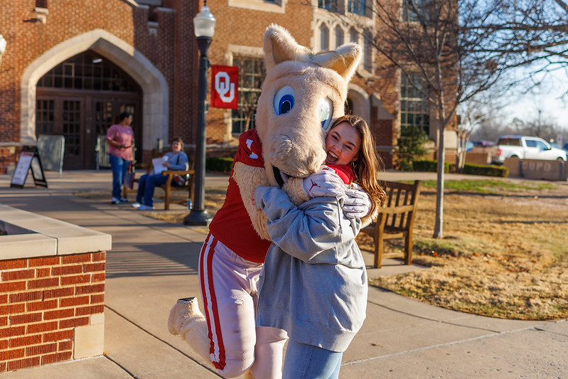 The OU mascotte Boomer hugs a OU student on Campus in a sunny day