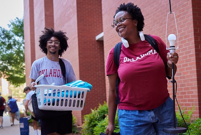 A son and mother carry items into the OU residence hall.