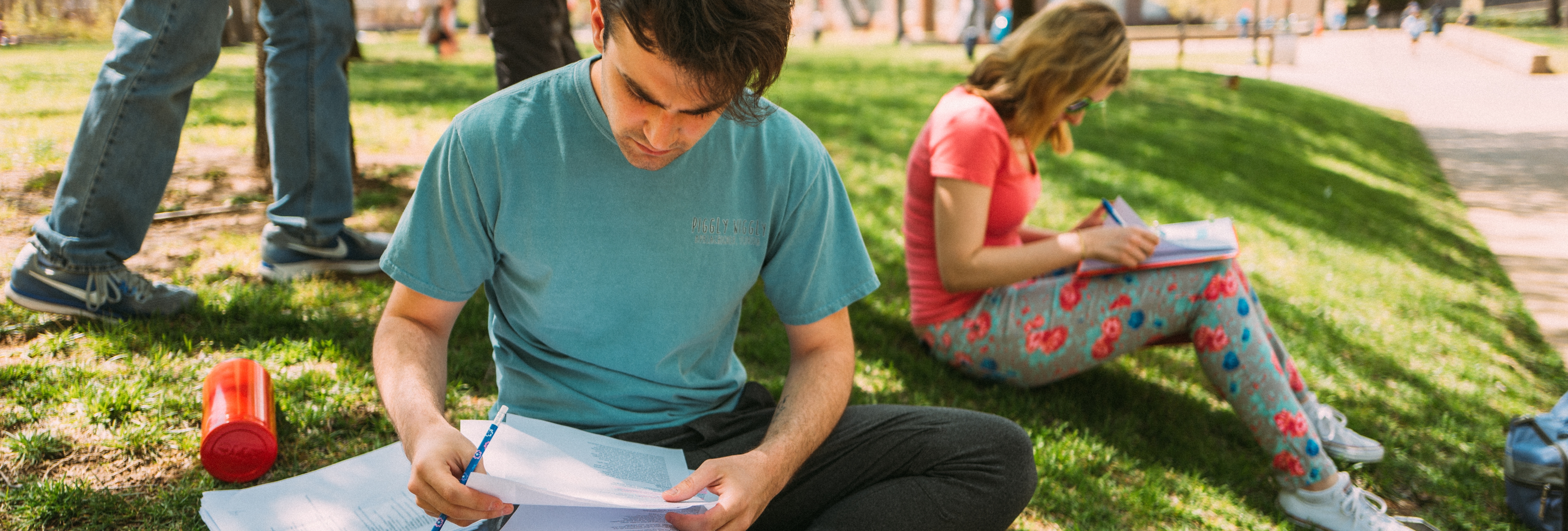 Two students studying on the grass. 