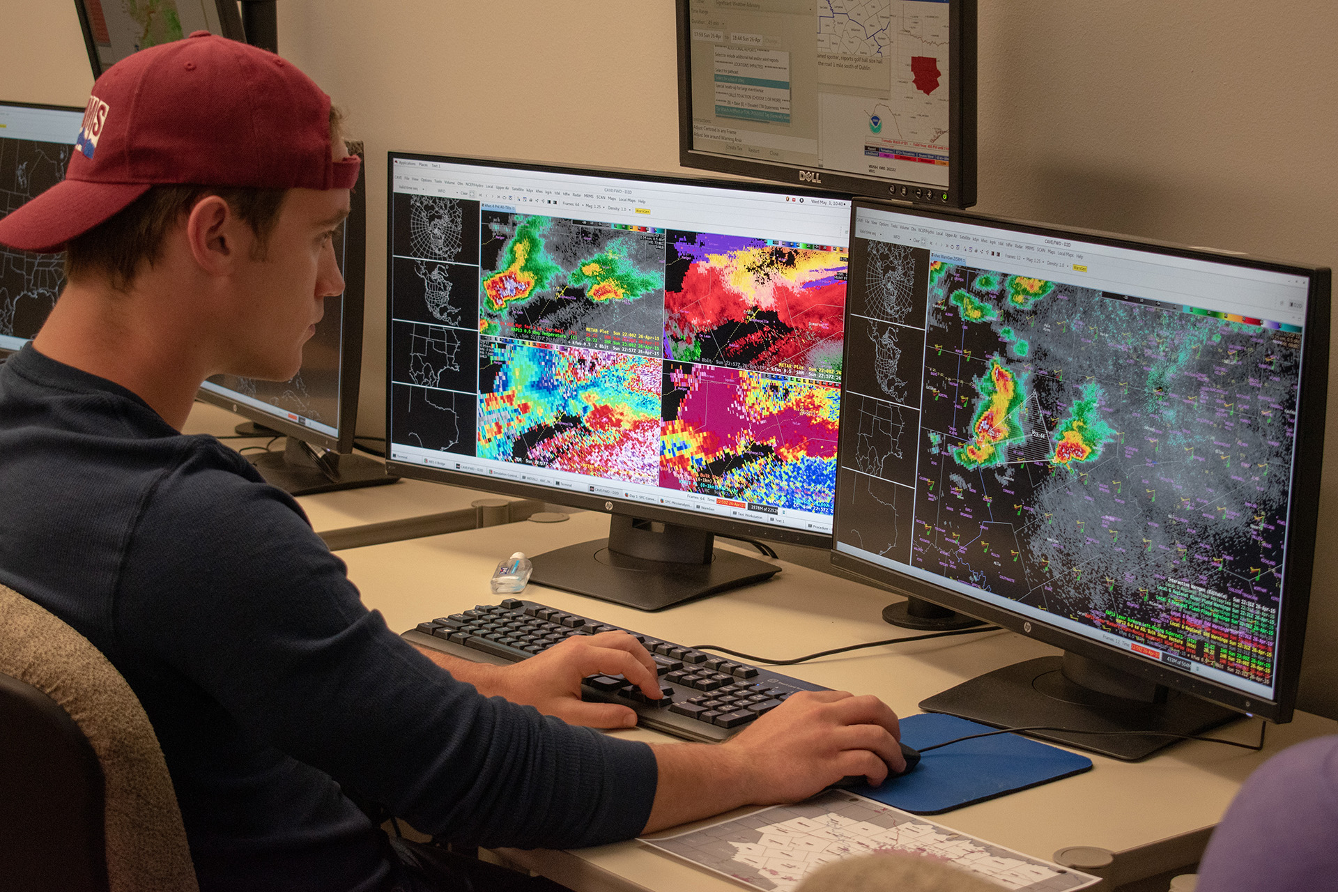 Meteorology student looking at two screens with weather radar displayed. 