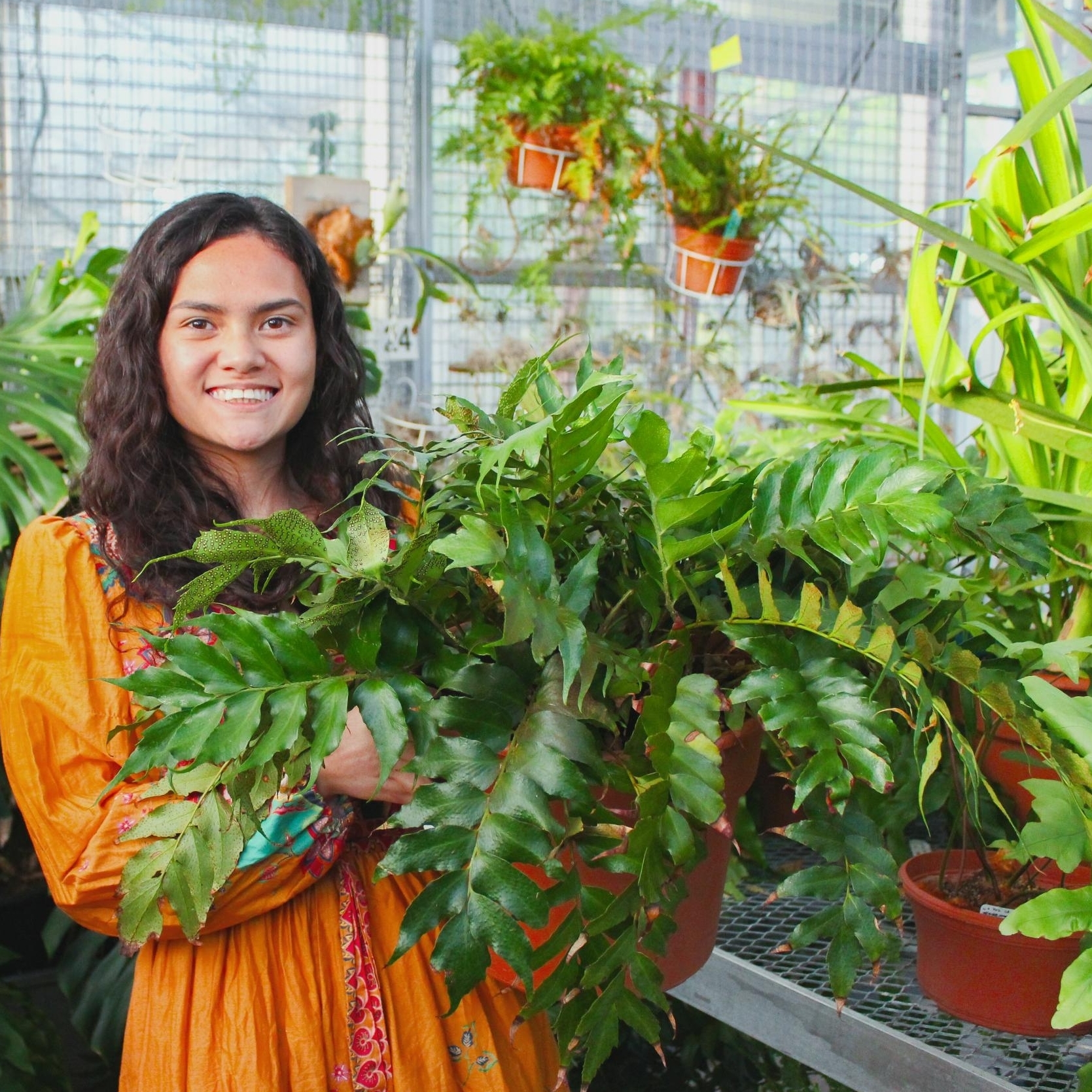 Headshot of Emani Rust in greenhouse with a fern.