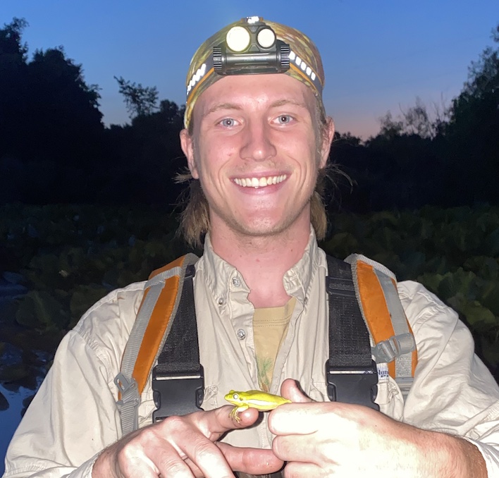 Owen with a headlamp holding a frog.