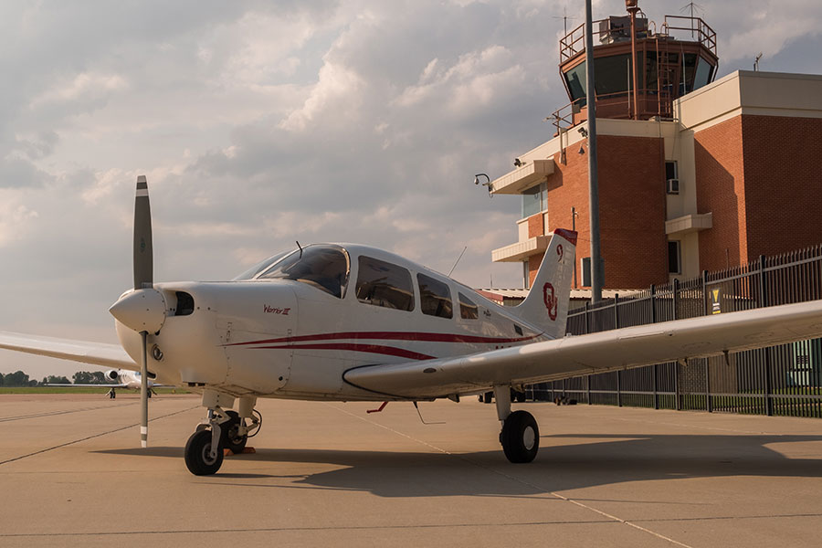 Small propeller plane on ground with a building in the back corner. 