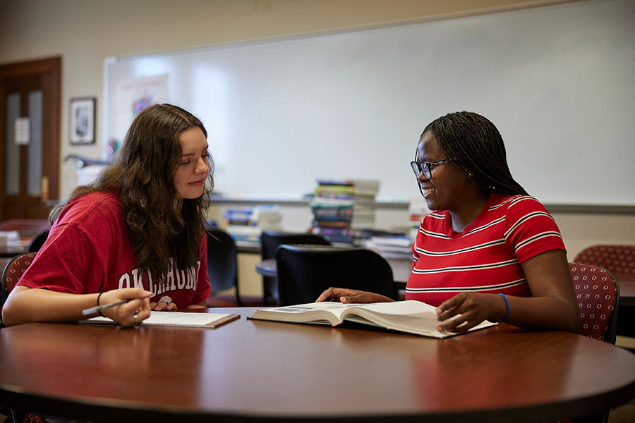 Two students sitting at a table, reading books.