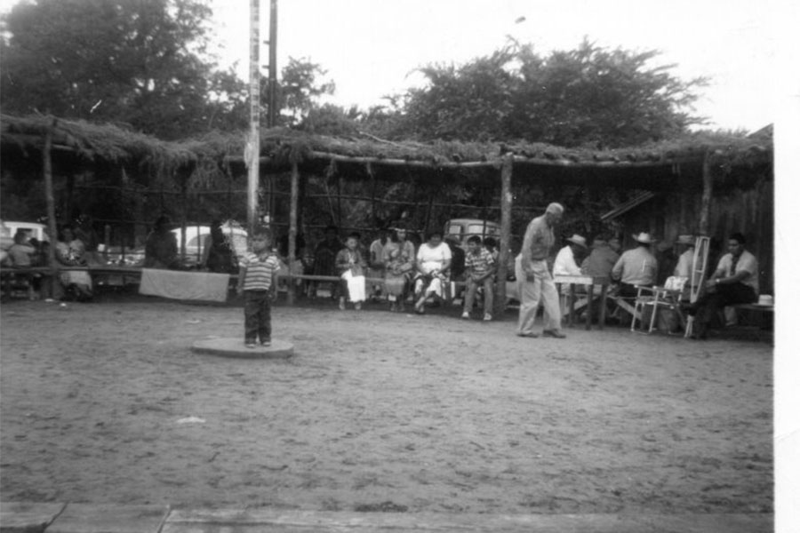 A family from Camp Creek around a flag pole, a child stands in front of the pole.