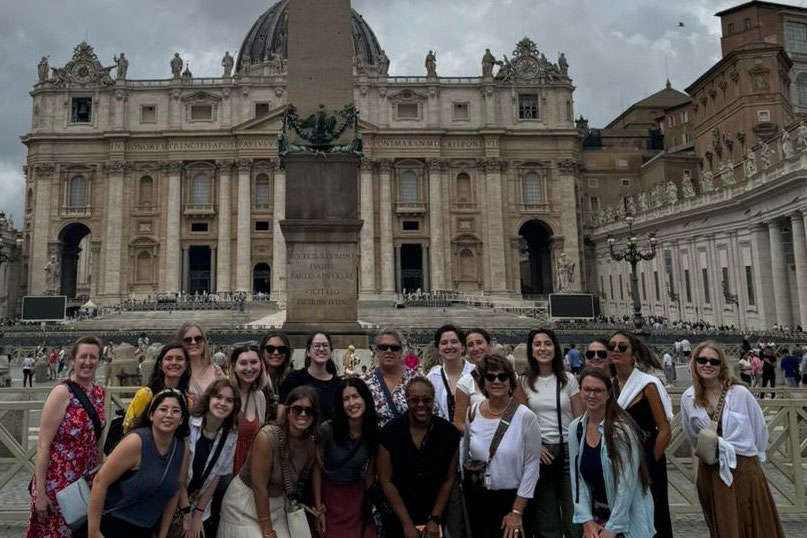 OU in Italy Summer 2024 class stand pose in front of limestone buildings in Italian square.