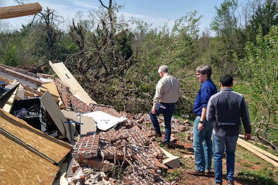 A group of people assess storm damage.