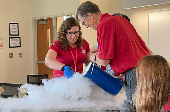 Student volunteer helping faculty professor with liquid nitrogen in Engineering Days demostration