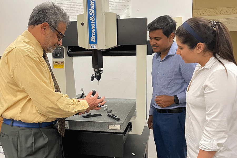 ISE Director Shiva Raman standing with two students at a piece of lab equipment.