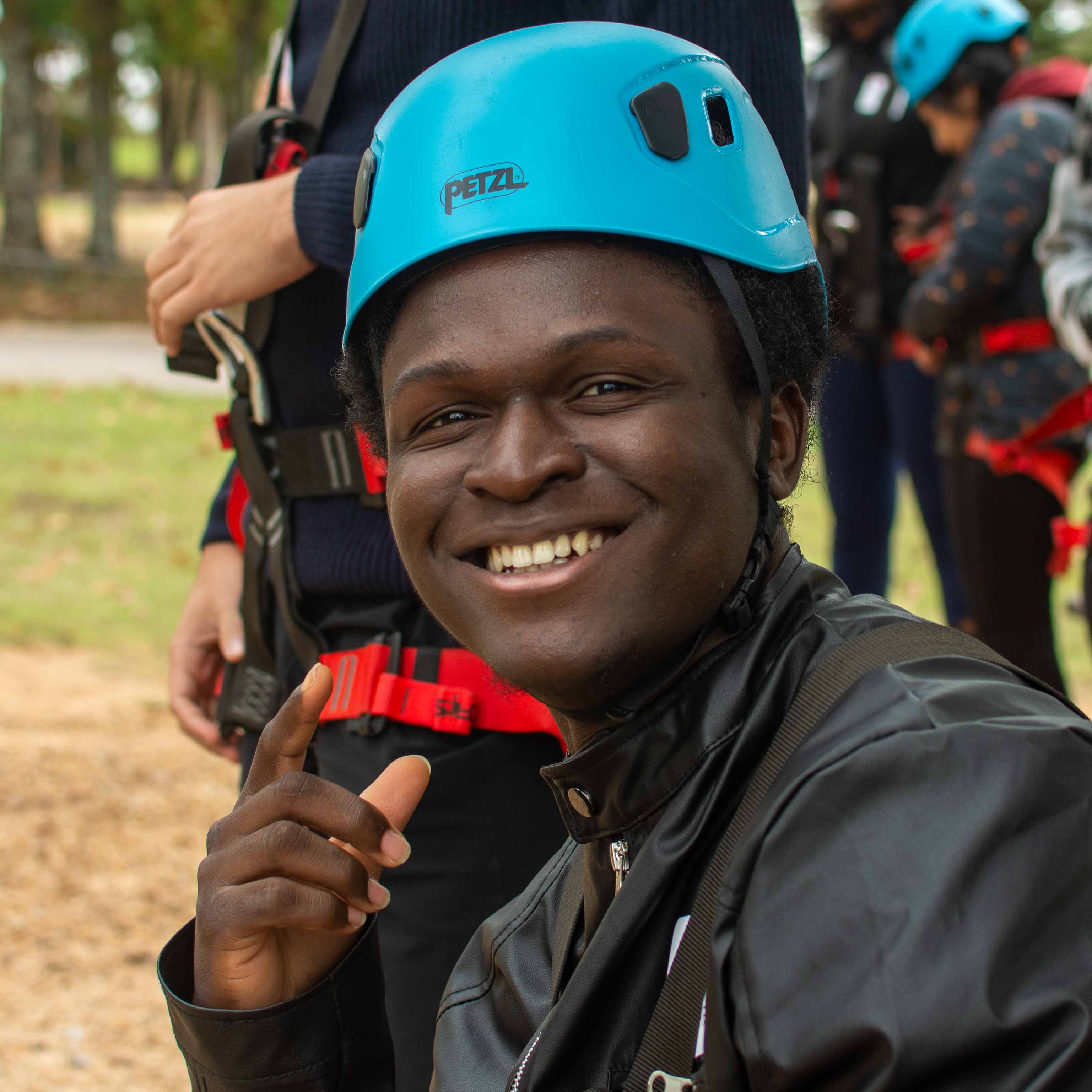 A man wearing a climbing helmet smiles for the camera.