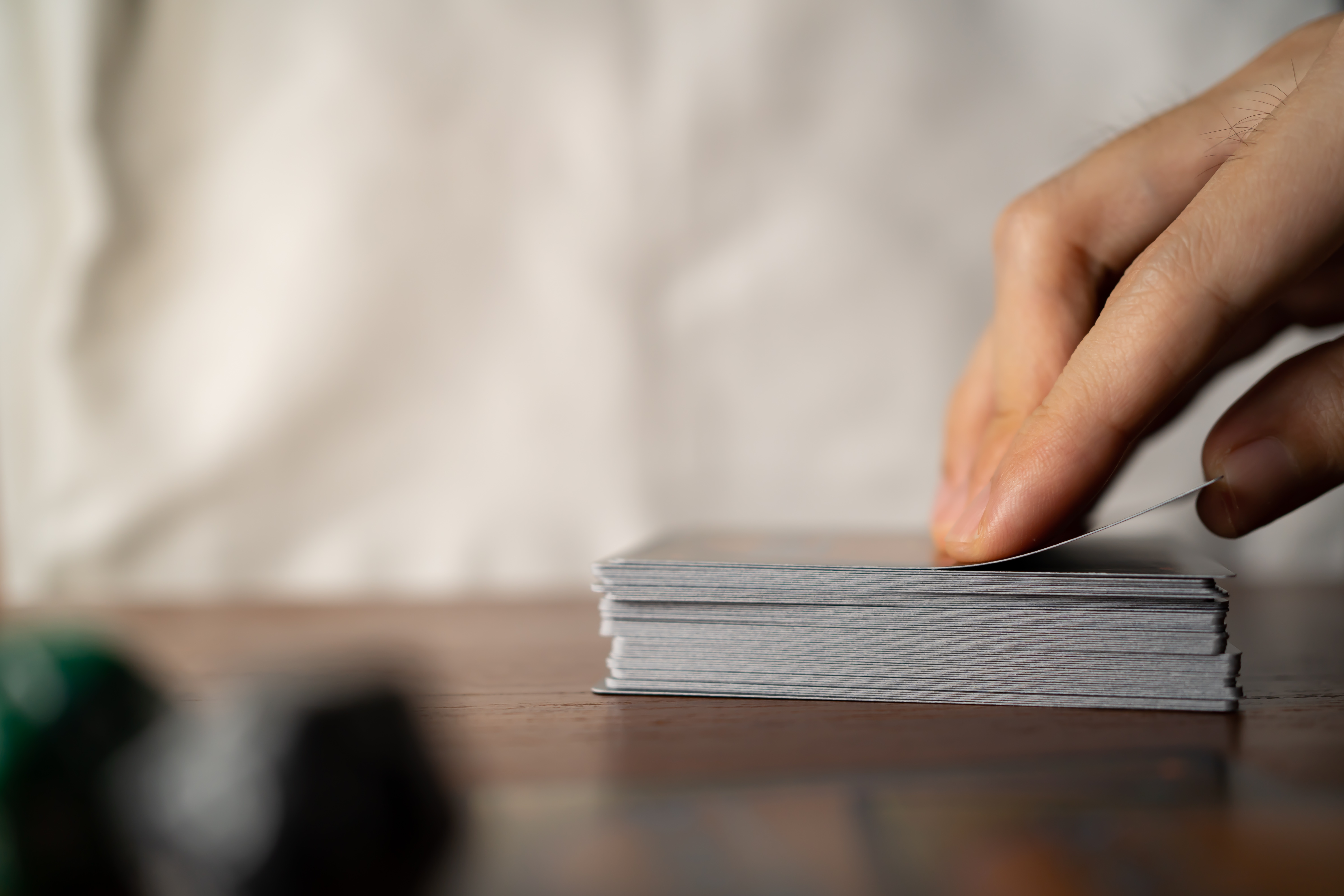 hand picking up a card from a deck on a table with dice in the front left corner. 