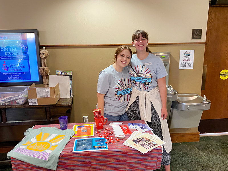 two students in blue shirts standing together and smiling for a photo