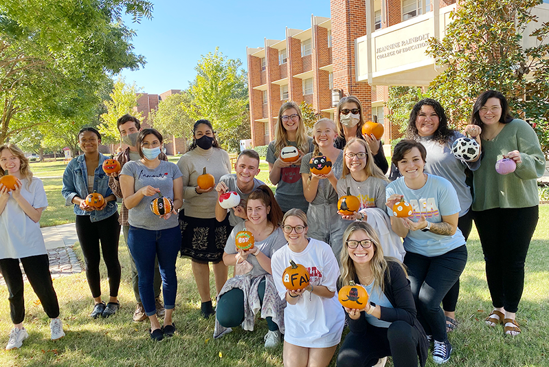 group of students in front of Collings Hall with pumpkins