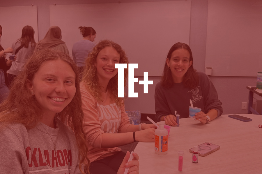 Three students working together at a table. Text overlay reads: TE+.