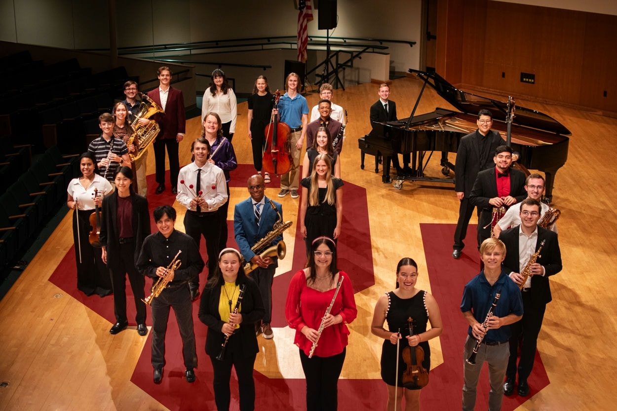 OU Music students standing on sharp hall stage with instruments in an OU formation.